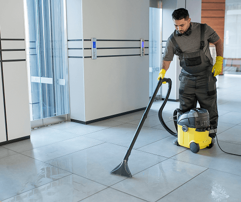 full shot man vacuuming office floor